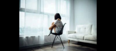 Woman sitting alone by window, reflecting on bipolar rapid cycling.