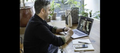 Man engaging in online therapy session via laptop at home.