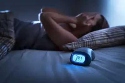 Alarm clock showing early morning hours as person struggles to sleep.