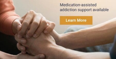 Hands clasped in support during addiction treatment session.